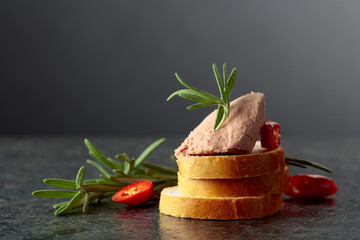 Bread slices with pate, red pepper, and rosemary.