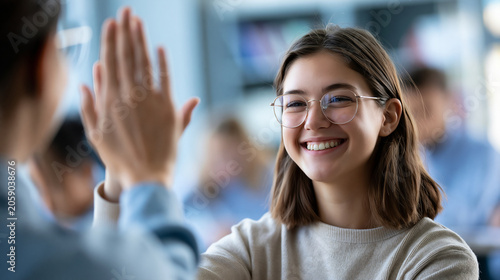 Faceless teacher giving a high-five to a smiling girl student in a classroom, celebration of academic achievement, defocused classroom interior in background, education mentorship