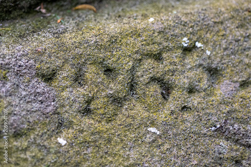 Eroded carving of the date 1865 on a weathered lichen-covered headstone in St Nicholas Church, Ashchurch, Gloucestershire