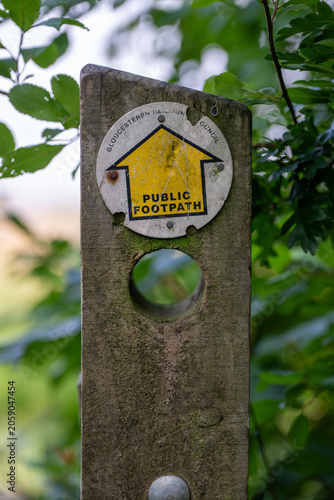 Gloucestershire public footpath waymarker disc on a weathered wooden post near Ashchurch, Tewkesbury, England