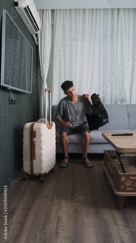 Temporary living and emotional exhaustion. Man sitting in rented apartment surrounded by luggage and uncertainty, vertical