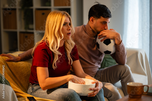 Fényképezés Couple watching intense soccer game at home