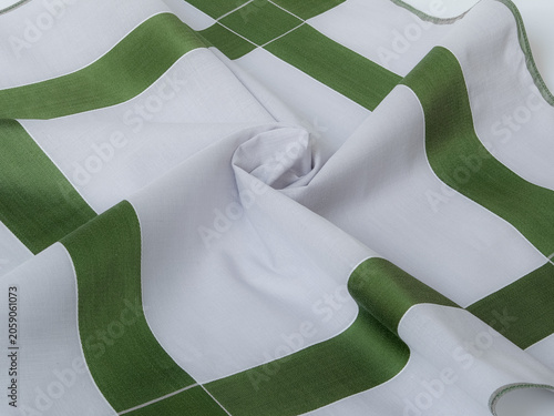 A macro close-up showcasing the delicate fabric texture, weave, and soft folds of a gray and green cross-patterned textile handkerchief.