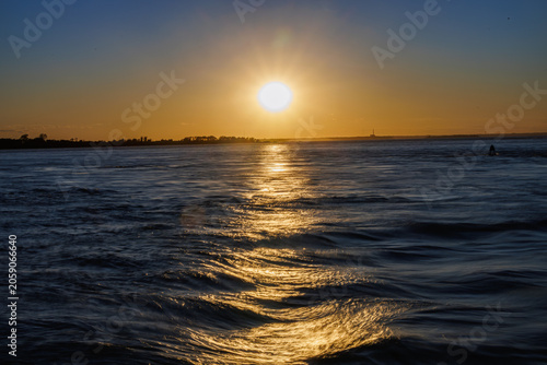 Golden sunset reflecting over rippling, wave-textured water