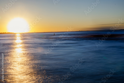 Sunset casting a bold light trail over a calm blue sea