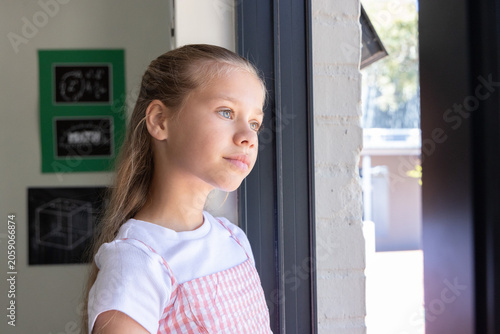 Photos Preteen girl standing inside by glass door near chalkboards, brick jamb, in pina