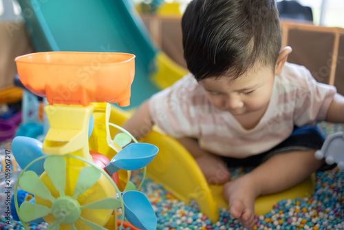 
Child plays with colorful plastic balls on yellow slide. Hands hold small tool, feet touch soft beads. Joyful, curious child explores playful, sensory environment. Perfect for preschool, therapy
