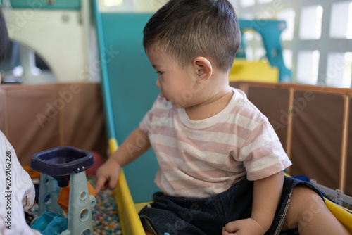 
Child plays with colorful plastic balls on yellow slide. Hands hold small tool, feet touch soft beads. Joyful, curious child explores playful, sensory environment. Perfect for preschool, therapy
