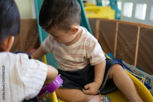 
Child plays with colorful plastic balls on yellow slide. Hands hold small tool, feet touch soft beads. Joyful, curious child explores playful, sensory environment. Perfect for preschool, therapy
