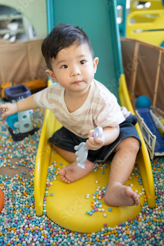 
Child plays with colorful plastic balls on yellow slide. Hands hold small tool, feet touch soft beads. Joyful, curious child explores playful, sensory environment. Perfect for preschool, therapy
