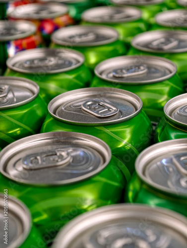 Green fizzy beverage cans stacked in organized order on retail shelves. Rows of green carbonated drink cans displayed on store shelves for easy selection