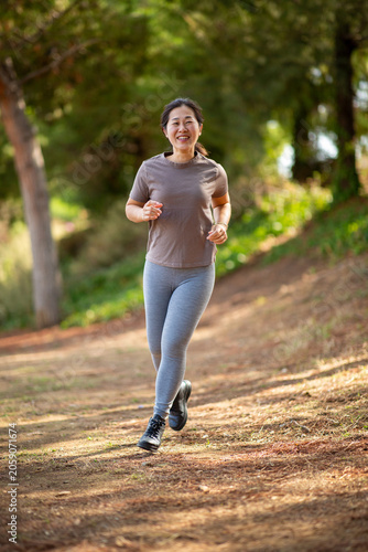 East Asian woman jogging on woodland trail