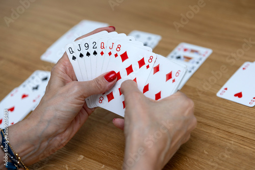 Woman's hands holding a fan of playing cards — card game, leisure, entertainment