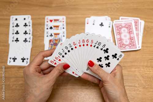 Woman's hands holding a fan of playing cards — card game, leisure, entertainment