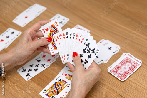Woman's hands holding a fan of playing cards — card game, leisure, entertainment