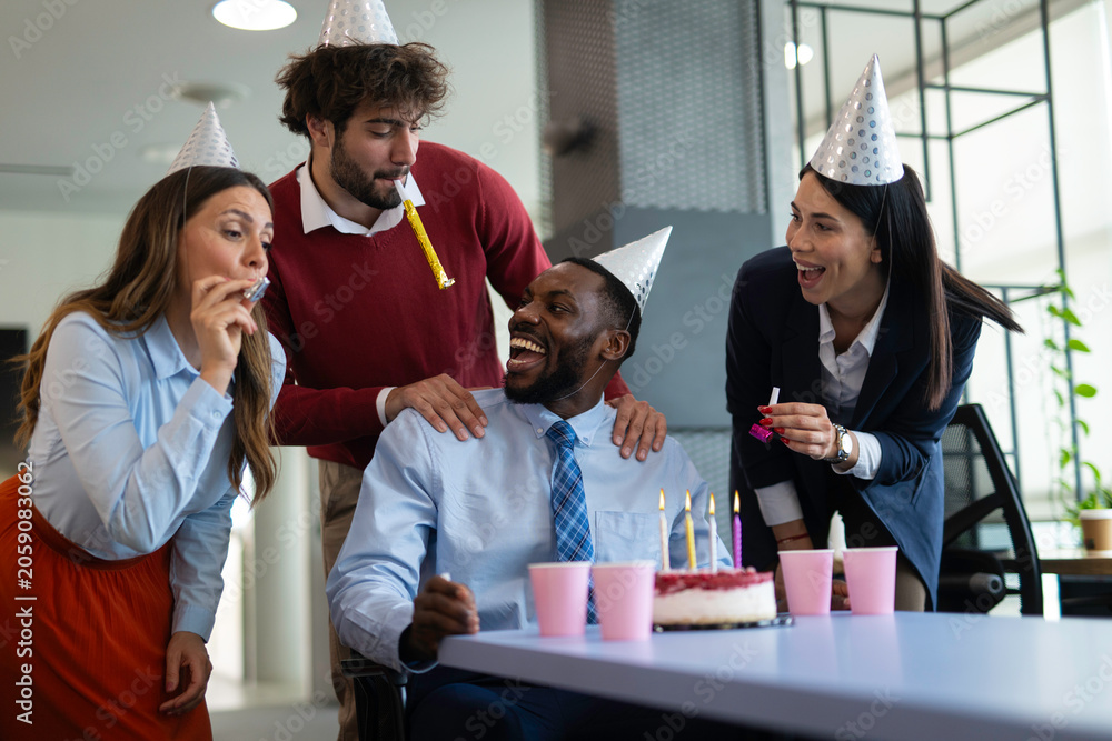 Fototapeta premium Coworkers celebrating office birthday party with cake and party hats