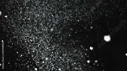 White snowflakes falling against a dark black background
