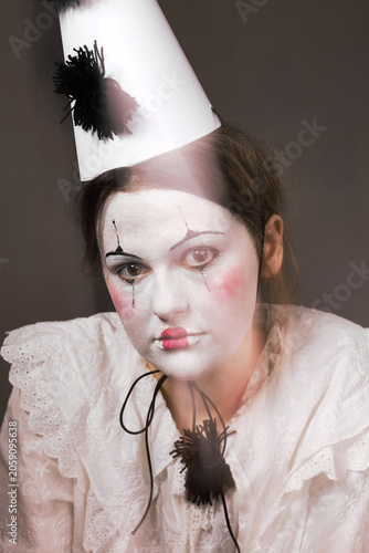 Muted portrait of sad clown woman with light leak looking at camera