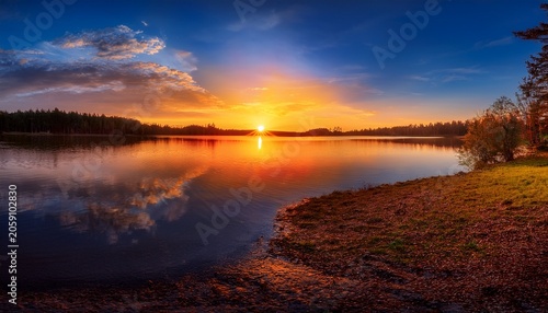 Vibrant Sunset Over Lake A Breathtaking Panorama Unfolds As The Sun Dips Below The Horizon Painting The Sky With Fiery Hues And Casting A Golden Glow Over The Serene Lake
