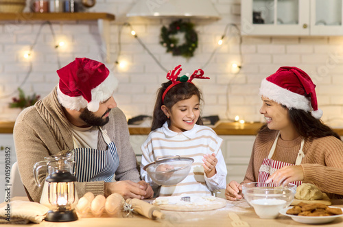 Obraz na plátne Christmas family baking cookies together at home kitchen with festive garlands