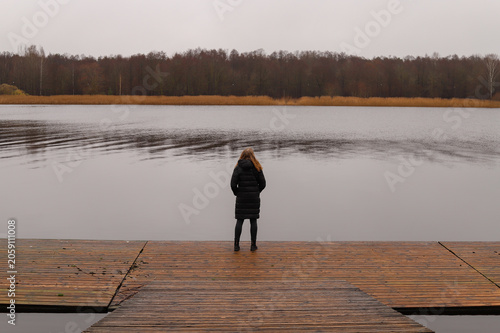 A lonely walk along a wooden pier by a calm lake in autumn