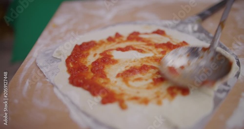 Pizza dough with sauce being prepared in a kitchen