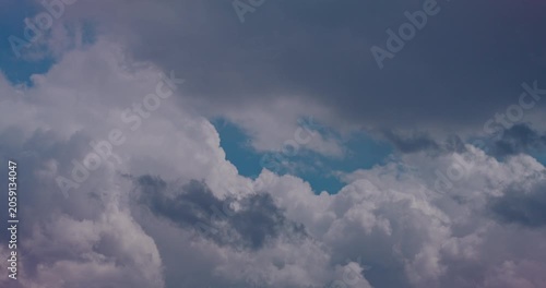 Bright cumulus clouds drifting across a calm blue sky in soft daylight