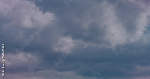 Bright cumulus clouds drifting across a calm blue sky in soft daylight