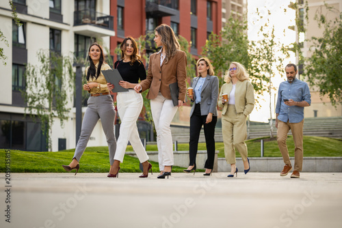 Group of professionals walking and talking in urban business district during coffee break