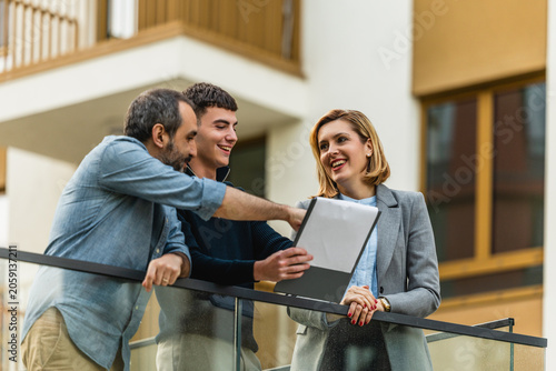Real estate agent showing apartment balcony to clients during friendly property viewing