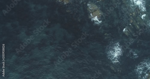 Drone photography capturing the graceful flight of seabirds over a rugged and mysterious coastal area
