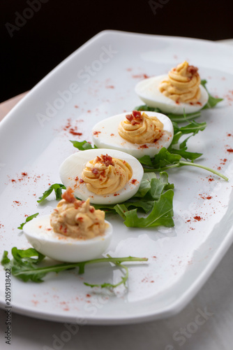 Classic Deviled Eggs Garnished with Greens and Paprika on White Serving Plate