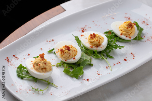 Gourmet Deviled Eggs Served on White Platter with Fresh Greens and Paprika