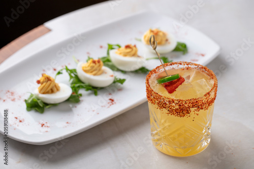 Spicy Citrus Cocktail with Deviled Eggs Appetizer on Elegant Restaurant Table