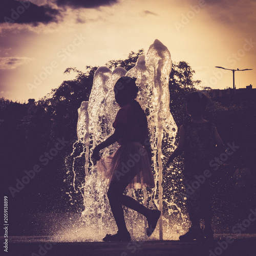 Children playing in a fountain at sunset