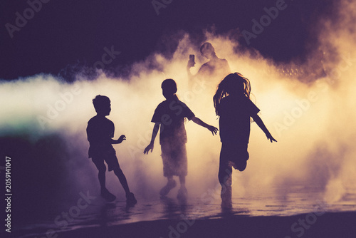 Children and people playing in a mystical fog at sunset