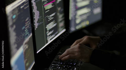 Coding in a dimly lit room with multiple computer screens