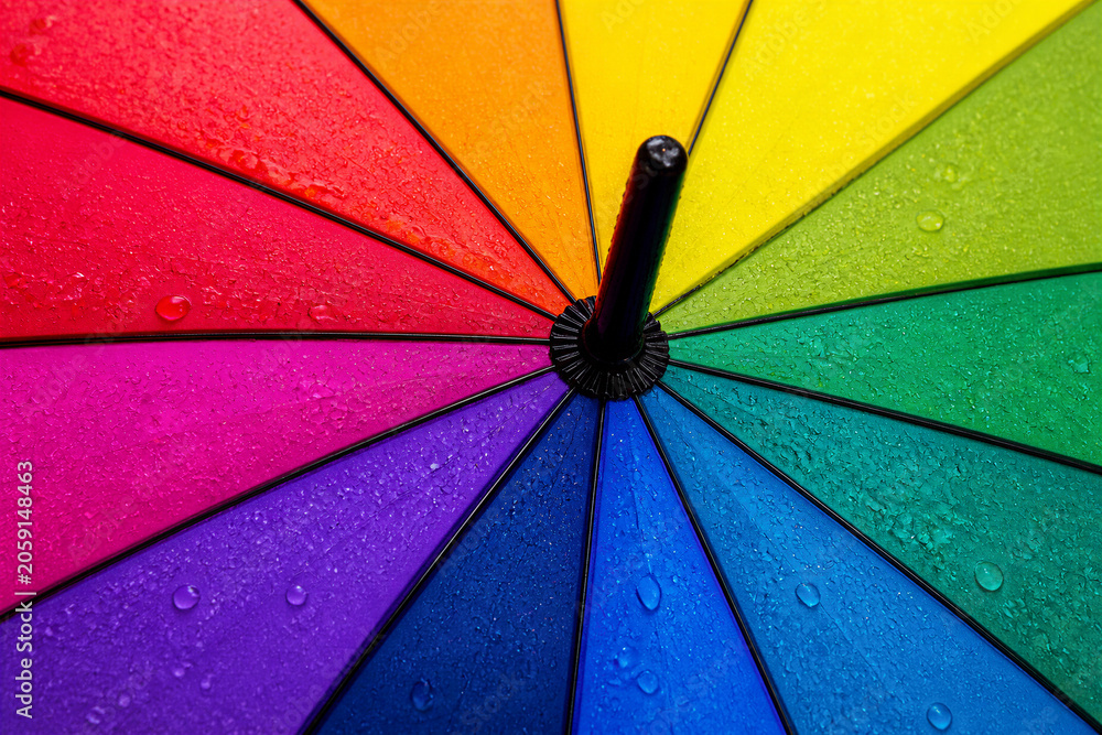 Fototapeta premium Rainbow umbrella canopy wet with water droplets in close up