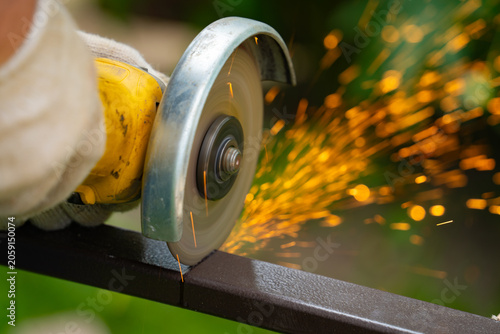 Canvastavla A man saws an iron pipe with a hand-held circular saw