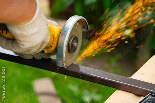 Konstfotografi A man saws an iron pipe with a hand-held circular saw