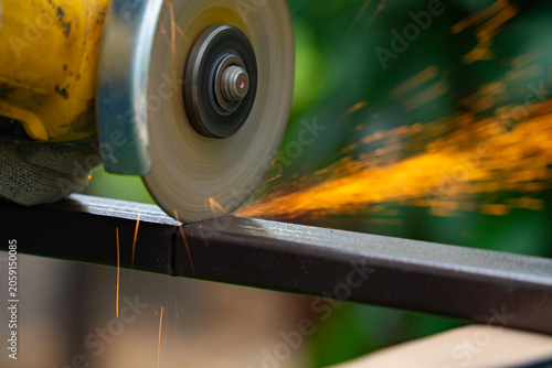 Billede på lærred A man saws an iron pipe with a hand-held circular saw