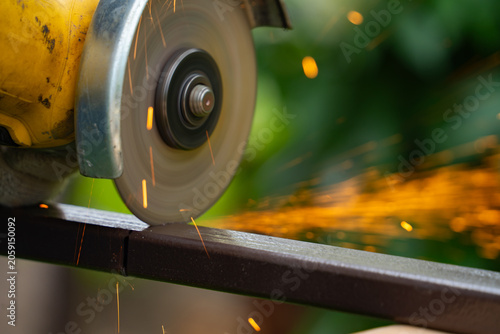 Billede på lærred A man saws an iron pipe with a hand-held circular saw