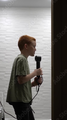 A guy sings while holding a hairdryer in his hand instead of a microphone. A teenager improvises in the bathroom with a hairdryer in hand. High quality FullHD footage