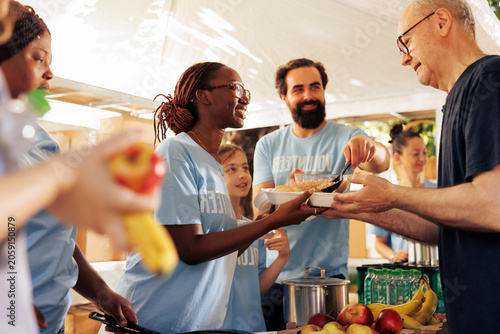 Photography Generous volunteers at food bank, distribute essential items and nourishments to needy; charity group giving meal donations, serving underprivileged and homeless people with compassion and kindness