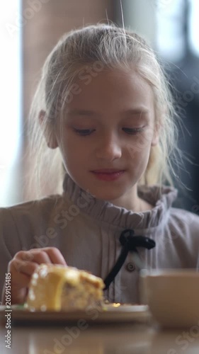 A happy girl takes a candle out of a cake. A child celebrates with her family at a cafe, blows out a candle, and takes it out. High quality FullHD footage