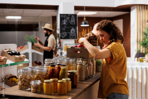 Photography Healthy living woman in zero waste shop looking to buy freshly handpicked apples and other fruits while customer shopping for chemicals free groceries in local neighborhood store