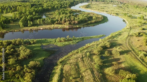 Scenic drone view of river bend and green fields in warm sunlight 4K