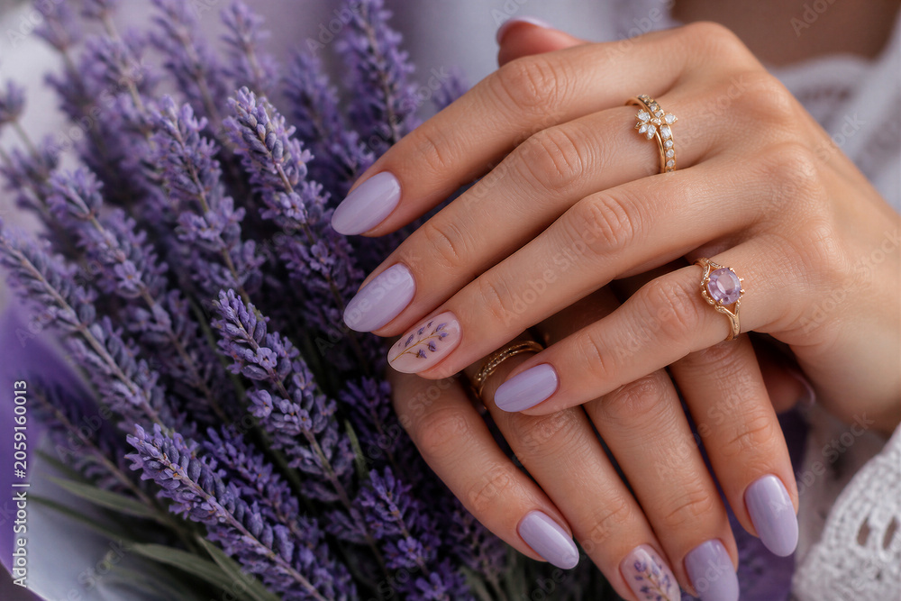 Fototapeta premium Woman hands displaying lavender manicure with floral bouquet