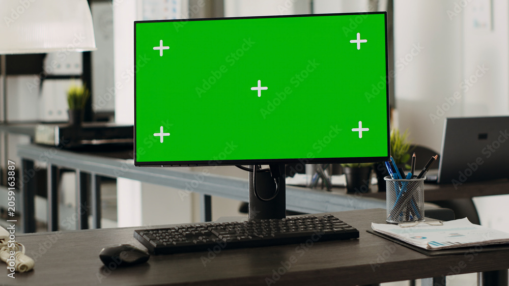 Fototapeta premium Workstation desk with green screen monitor in business agency office, empty coworking space with modern gadgets used for company operations. Computer showing chroma key and mockup template on display.