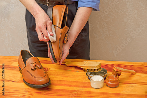 Hands of Professional Male Shoes Cleaner with Cleaning Accessories Shoe Wax, Cream and Brushes For Tan Calf Leather Tassel Loafers Shoes
